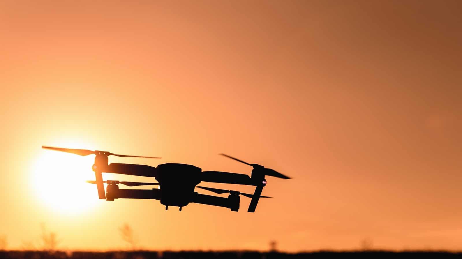 A photo silhouette of a drone in front of the sun.