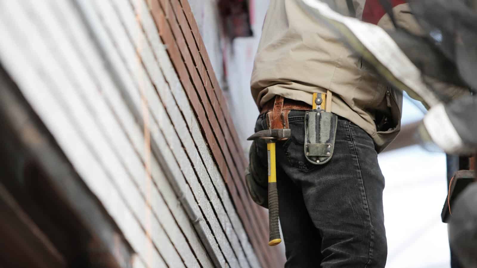 A photo of a contractor wearing a tool belt with a hammer.