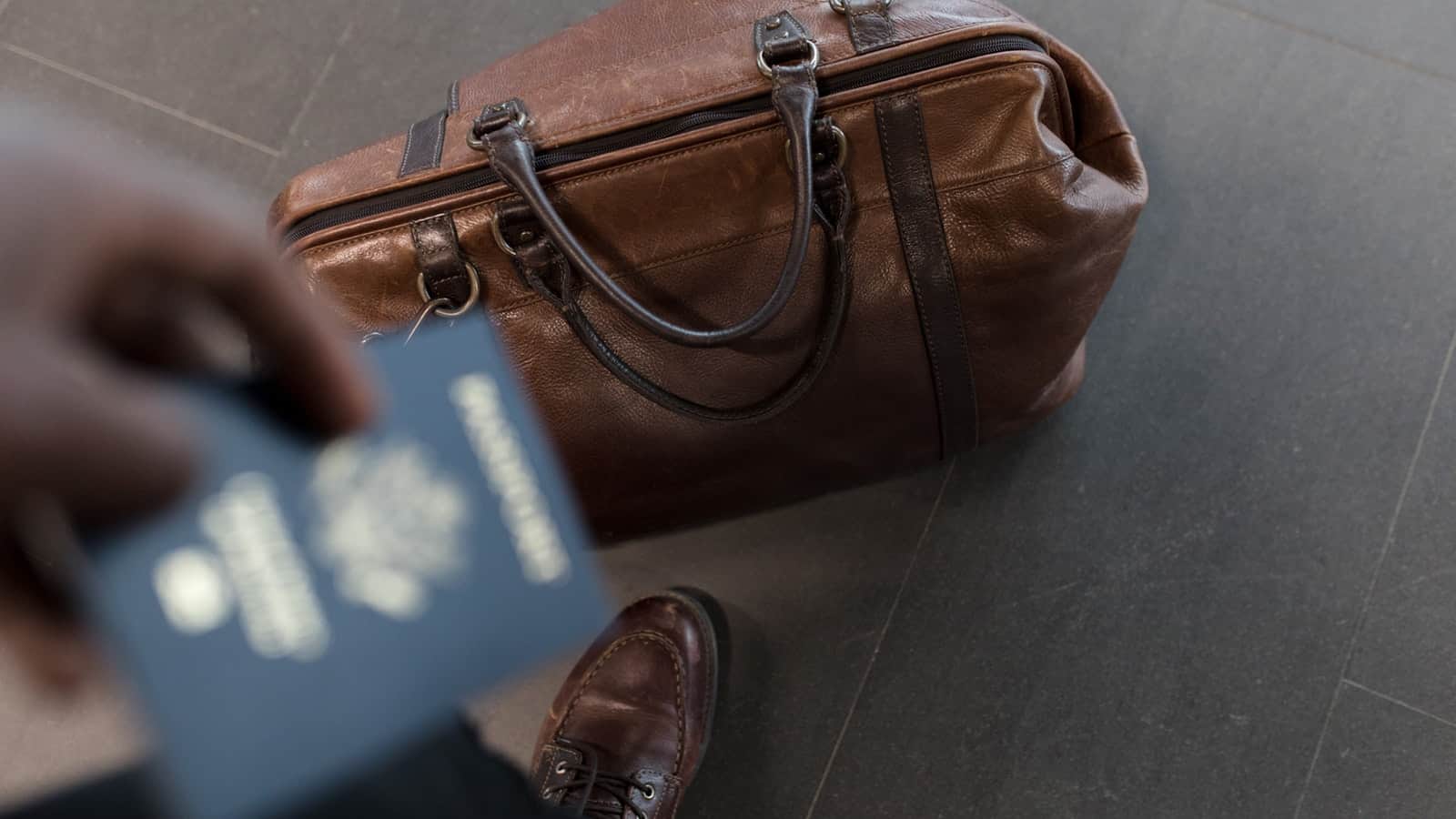 A photo looking down at an individual's luggage and passport.