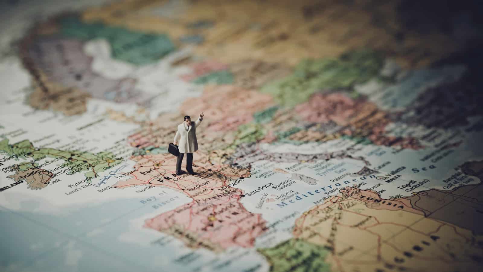 A photo of a miniature figure standing on France on a map of Europe.