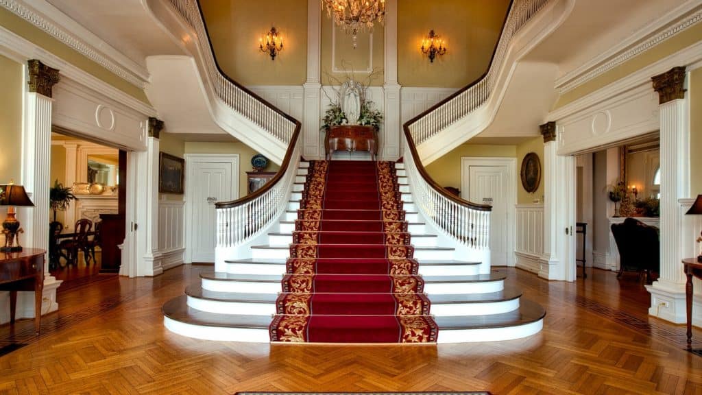 A photo of a carpeted grand staircase in an affluent home.