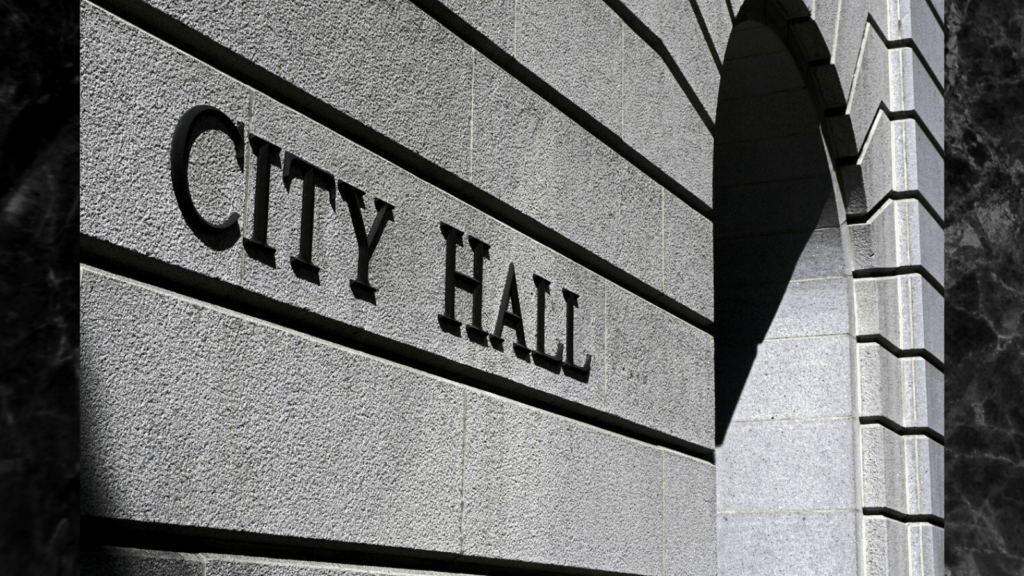 A black and white photo of a building with the sign 'City Hall'.