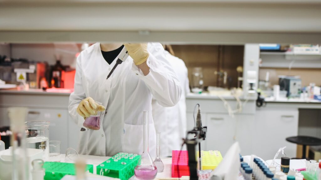 A photo of a scientist holding a beaker of fluid in a lab.