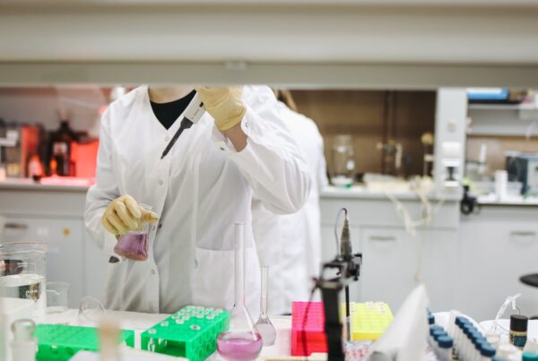 A photo of a scientist holding a beaker of fluid in a lab.