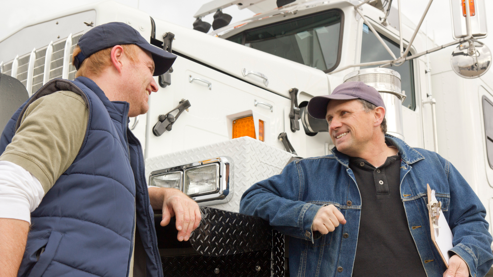 A photo of employees leaning on the fender of a semitruck.